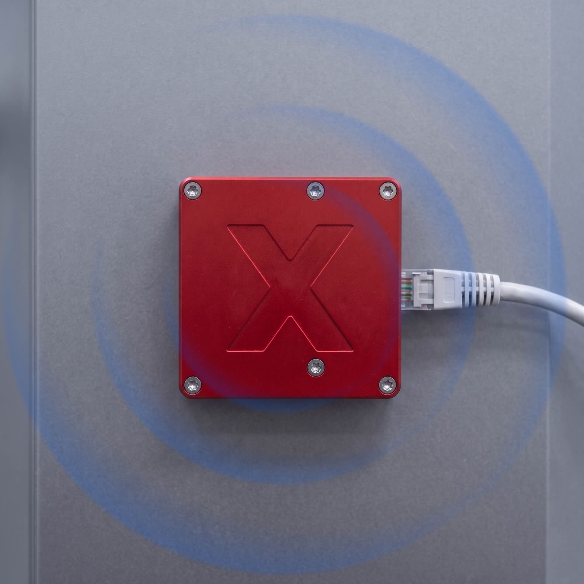 SensorX-Sensor auf einem Maschinenpanel, um ihn herum ein dargestelltes Funksignal und ein angeschlossenes Datenkabel