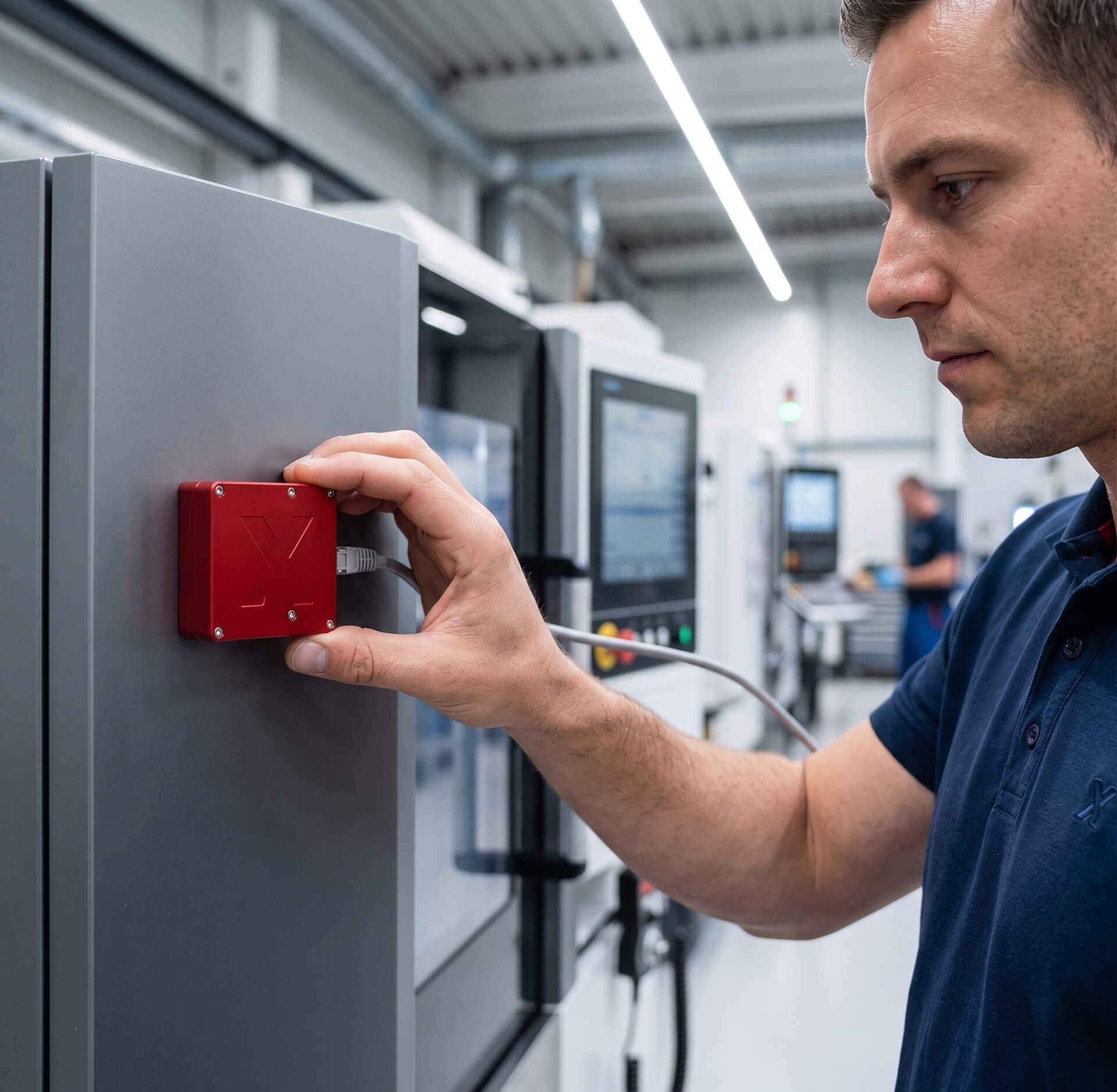 Technik přikládá senzor SensorX zvenčí na rozvaděč obráběcího stroje a zapojuje kabel